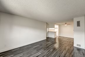 Fullerton apartment for rent - an empty living room and kitchen with wood flooring and a ceiling fan