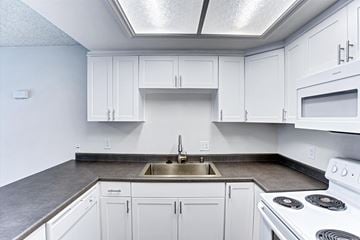 Fullerton apartment for rent - A kitchen with white cabinets and a stove top oven.