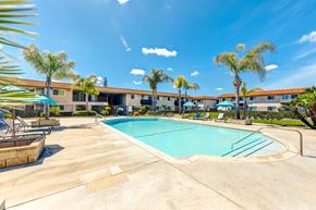 Fullerton apartment for rent - a swimming pool with palm trees and a building in the background