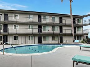 Fullerton apartment for rent - A pool is surrounded by a concrete patio and a building with balconies.