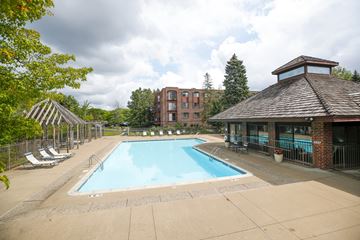 Bloomington apartment for rent - A large outdoor swimming pool surrounded by a fence and trees.