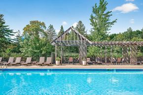Bloomington apartment for rent - A pool with a wooden structure and chairs around it.