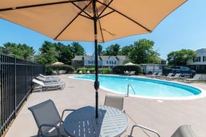 Manassas apartment for rent - A pool with a table and chairs under an umbrella.