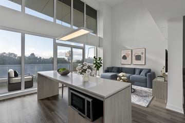 Toronto apartment for rent - A modern kitchen with a large island and a view of trees outside the window.