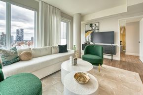 Toronto apartment for rent - A living room with a white sofa, green armchair, and a white coffee table.