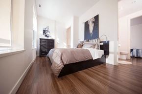 Calgary apartment for rent - A bedroom with a large bed, a dresser, and a painting on the wall.