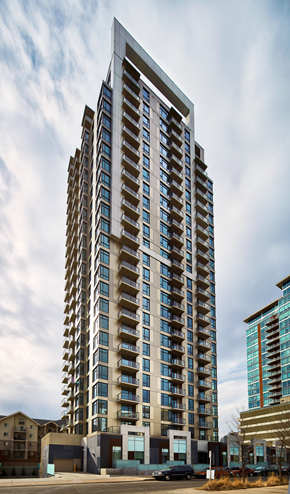Calgary apartment for rent - A tall building with many windows is in the foreground.