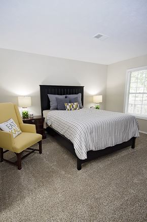 Duluth apartment for rent - A bedroom with a bed, chair, and lamp.