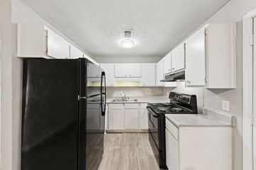 Clarkston apartment for rent - A black refrigerator is in a kitchen with white cabinets.