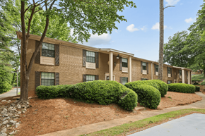 Decatur apartment for rent - Apartment building with green trees and bushes in front.