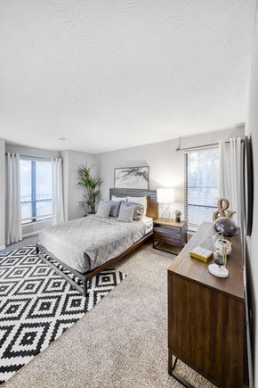 Stone Mountain apartment for rent - A bedroom with a bed, nightstand, and a rug with a geometric pattern.