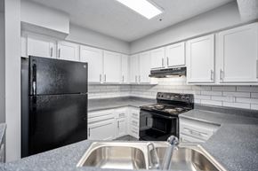 Lithonia apartment for rent - a kitchen with white cabinets and black appliances