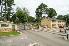 Riverdale townhouse for rent - A gated entrance to a residential area with houses and trees.