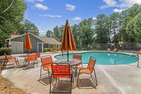 Stone Mountain apartment for rent - A poolside table with chairs and umbrellas is set up next to a swimming pool.