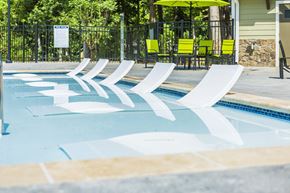 Atlanta apartment for rent - a swimming pool with three white chairs in it