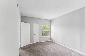 Charlotte apartment for rent - A room with a carpeted floor and a window showing trees outside.