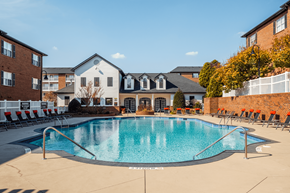 Charlotte apartment for rent - A swimming pool surrounded by lounge chairs and buildings in the background.
