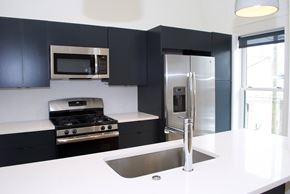 Philadelphia apartment for rent - a kitchen with black cabinets and stainless steel appliances and a white counter top