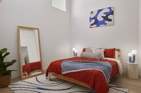 Philadelphia apartment for rent - A bedroom with a red bedspread and a blue and white abstract painting on the wall. at 1600 Callowhill, Philadelphia, PA
