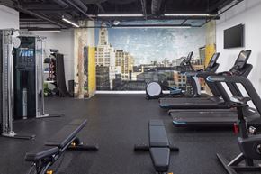 Philadelphia apartment for rent - A gym with treadmills, weights, and a city view mural on the wall.at 1600 Callowhill, Philadelphia, PA