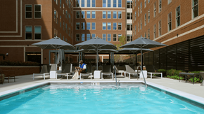 Philadelphia apartment for rent - A swimming pool surrounded by chairs and umbrellas in a courtyard.