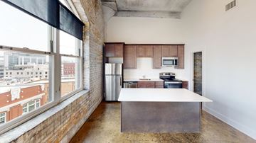 Fort Wayne apartment for rent - A kitchen with a brick wall and a window overlooking a cityscape.