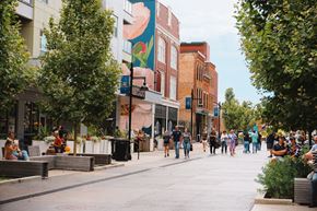 Fort Wayne apartment for rent - A street scene with people walking and sitting on benches.