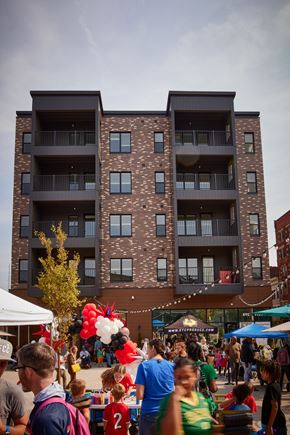 Cincinnati apartment for rent - A large building with balconies is behind a crowd of people.