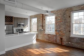 Cincinnati apartment for rent - an empty room with a kitchen and a exposed brick wall
