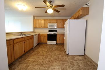Waukee apartment for rent - A kitchen with a white refrigerator and wooden cabinets.