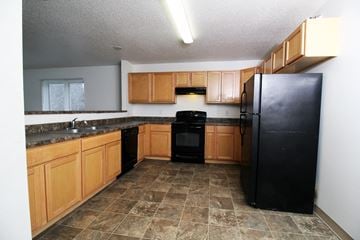 Des Moines apartment for rent - A kitchen with black appliances and wooden cabinets.