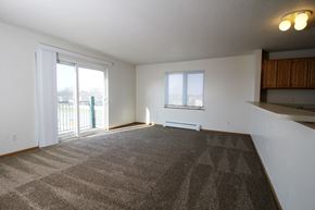 Waukee apartment for rent - an empty living room with a sliding glass door and a balcony