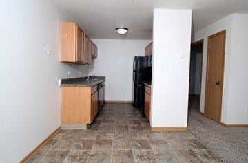 Des Moines apartment for rent - A kitchen with a black fridge and wooden cabinets.