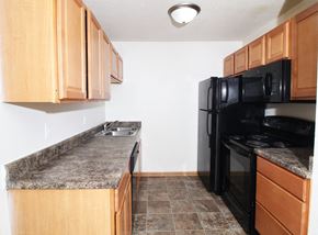 Des Moines apartment for rent - a kitchen with wood cabinets and black appliances