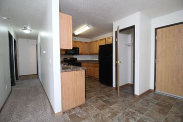 Des Moines apartment for rent - A kitchen with a black refrigerator and wooden cabinets.