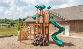 Des Moines apartment for rent - a playground with a slide and climbing equipment in front of a brick building