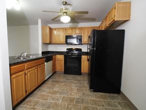 Des Moines apartment for rent - a kitchen with wood cabinets and black appliances