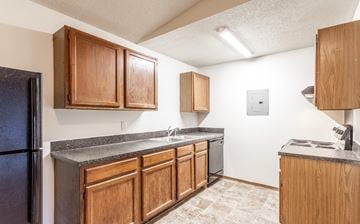 Des Moines apartment for rent - A kitchen with wooden cabinets and a black refrigerator.