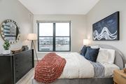 Ann Arbor apartment for rent - a bedroom with a large window and a bed with a blanket and pillows at Beekman on Broadway, Ann Arbor, MI