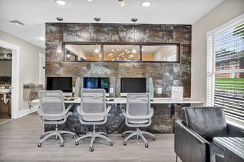 An office with a long desk with computers and chairs