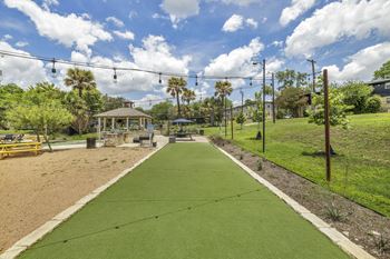 A green pathway leads to a gazebo in a park with palm trees