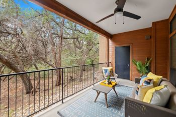 Covered balcony with seating overlooking wooded area