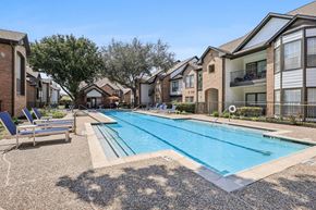 Houston apartment for rent - A swimming pool surrounded by apartment buildings and lounge chairs.