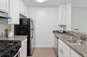 Valley Village apartment for rent - A kitchen with a black refrigerator and white cabinets.