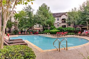 Houston apartment for rent - a swimming pool with chairs and trees and an apartment building in the background at Stone Creek at Old Farm Apartments, Houston, TX