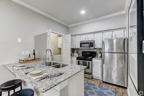 Houston apartment for rent - A kitchen with a granite countertop and stainless steel appliances.