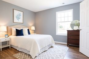 Charlotte apartment for rent - A bedroom with a white bed and a white nightstand with a lamp.
