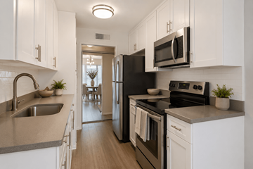 Sherman Oaks apartment for rent - A kitchen with white cabinets and black appliances.