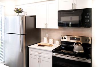 A kitchen with white cabinets and black appliances and a refrigerator