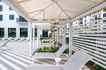 A patio with two lounge chairs and a white building